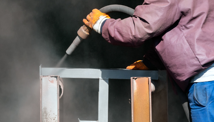 Worker Blasting Surface Contaminants From Metal